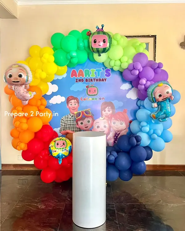 A vibrant Cocomelon themed birthday party featuring a full rainbow balloon ring. This setup includes a custom backdrop with all the main characters and is perfect for a colorful and fun second birthday celebration.