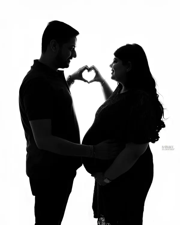 A classic and sweet silhouette. The heart-hands pose against a bright white background creates a simple, iconic image celebrating your love and new arrival.