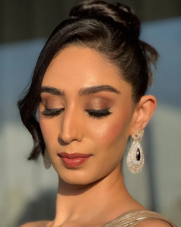 A close-up of this stunning cocktail look, captured in the golden hour light. Notice the seamless blend of the smokey eyeshadow, the precise highlight on the cheekbones, and the soft matte lip. This is HD makeup designed to look impeccable from every angle.