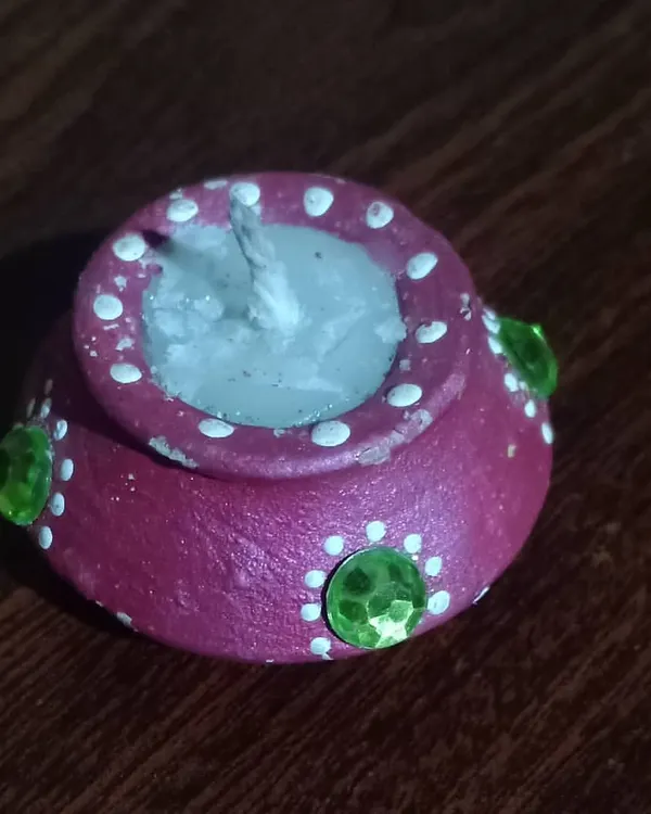 A close-up of my handmade terracotta diya candle. I paint each pot and fill it with wax to offer a modern, reusable, and eco-friendly alternative to disposable diyas for Diwali.
