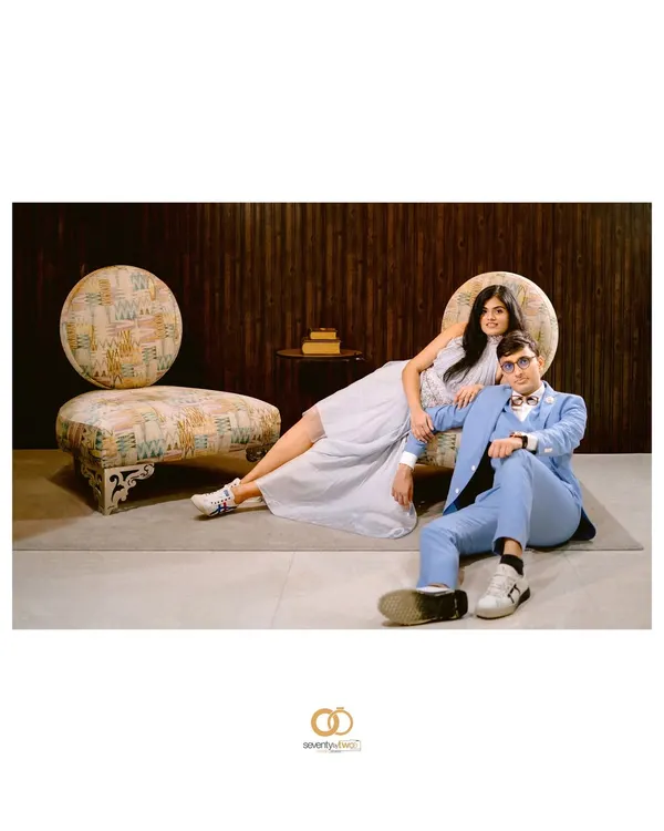 A wide, editorial-style shot that feels like a page from a high-fashion magazine. The composition, the furniture, and their poses all come together to create a cool, stylized portrait.