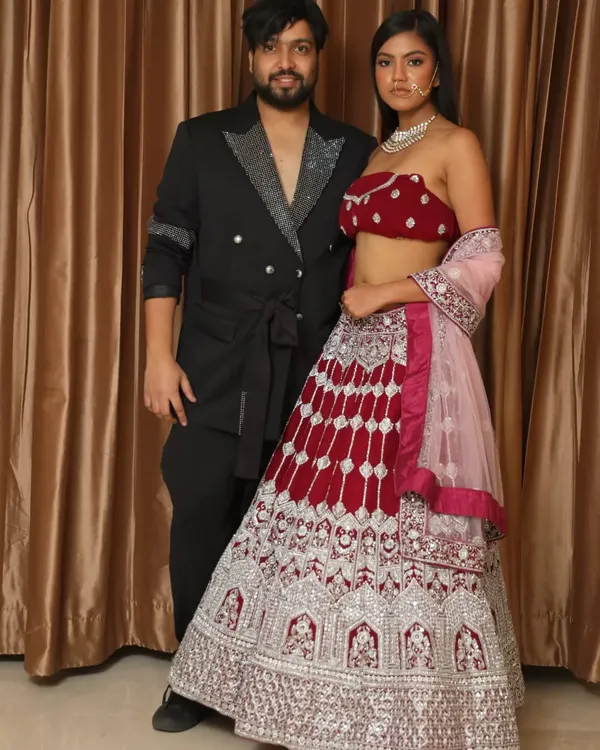 Standing with a model in one of my signature bridal lehengas. This piece features a rich red velvet blouse and a heavily embroidered skirt with intricate silver threadwork, perfect for a royal wedding look.