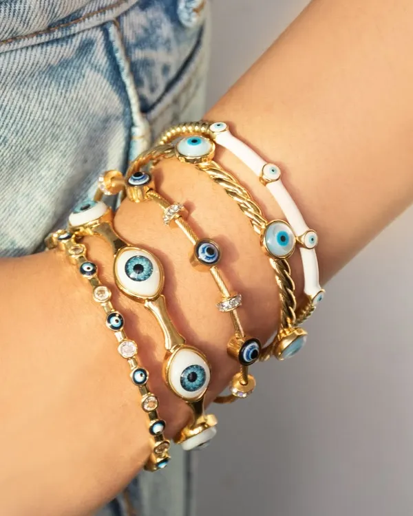 An arm full of protection. This image shows a stunning stack of our evil eye bangles in various styles, from classic blue and white enamel to twisted rope designs.