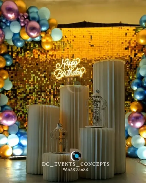 A glamorous birthday setup featuring a gold sequin shimmer wall and a colorful balloon frame. The custom pedestals and neon 'Happy Birthday' sign make this a fun and stylish centerpiece for any party.