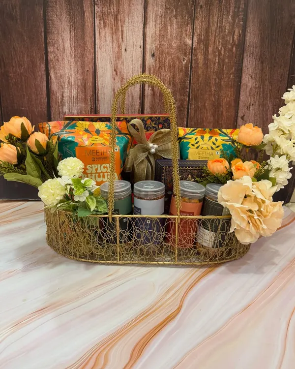 Have a 'chatpati and meethi' Rakhi with our desi snack hampers. This one is overflowing with a variety of traditional bites with a modern twist, all arranged in a beautiful wire basket with flowers.