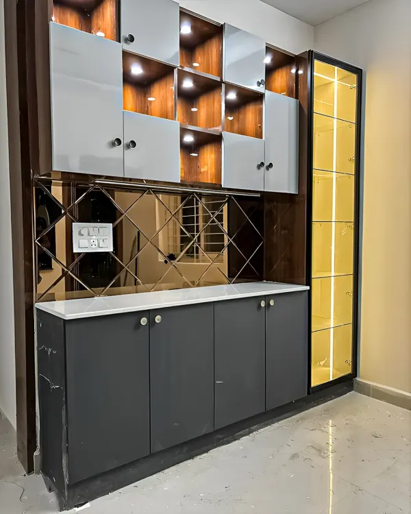 A modern crockery unit in a striking combination of grey, white, and yellow. This piece features a mix of closed cabinets, open-lit display niches, and a mirrored backsplash for a touch of glamour.