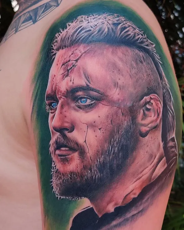 A hyper-realistic color portrait tattoo of a character from the show 'Vikings', done by guest artist Guru Pujar at our studio. The detail in the eyes and skin texture showcases a high level of skill.