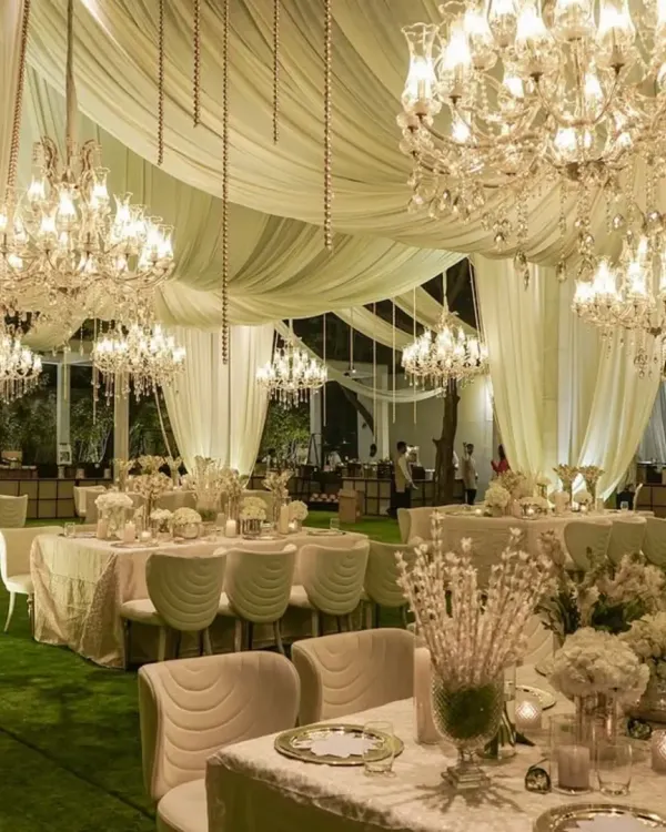 A breathtaking view of an all-white reception tent. We used flowing fabric drapery, dozens of crystal chandeliers, and lush white floral centerpieces to create a dreamy, ethereal environment.