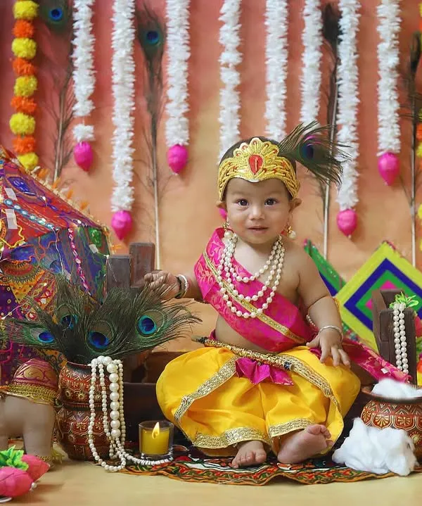 My studio is filled with props to create the perfect Janmashtami theme. This little Krishna is surrounded by peacock feathers, a decorated umbrella, and marigold garlands for a truly festive feel.