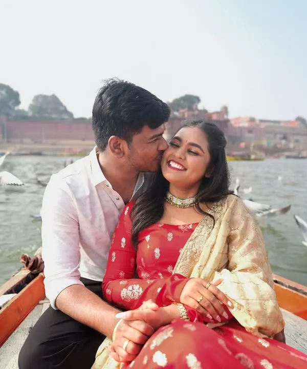 A candid moment of affection on a boat in Varanasi, with seagulls flying past. These are the unscripted, joyful moments that make a pre-wedding shoot special.