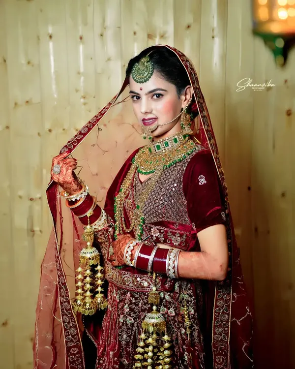 A stunning full-length portrait of a bride in her magnificent red velvet lehenga, showcasing the traditional kalire. I make sure to capture the entire bridal look in its full glory.
