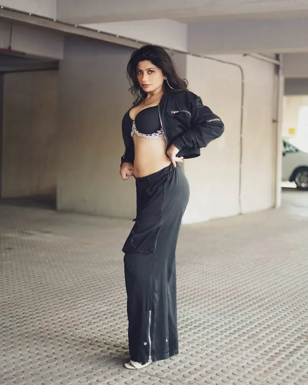 A full-body profile of model Shilpy Tyagi in a parking garage. The industrial setting contrasts with her fashion-forward look, creating a cool, urban aesthetic.