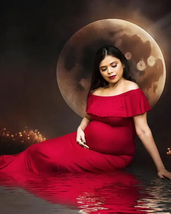 This portrait captures the magic of motherhood with a dramatic, fine art approach. I used a rich red gown and a creative moon backdrop to create a celestial, dream-like scene, focusing on the quiet and powerful connection between you and your baby.