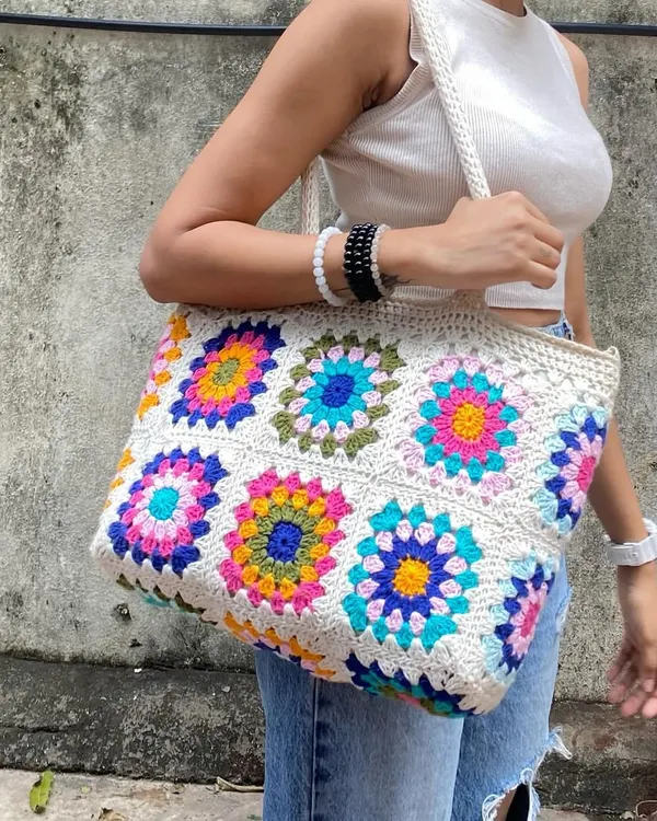 This is our spacious granny square tote bag, our absolute bestseller. It's inspired by the colorful designs you see all over Pinterest and is roomy enough to carry your world. We make each floral square by hand, and you can even customize the colors.