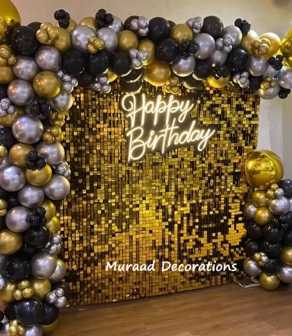This premium birthday decoration features a stunning gold sequin wall as the backdrop. It's framed by a balloon garland in black, silver, and gold, with a neon 'Happy Birthday' sign for that extra touch of class.