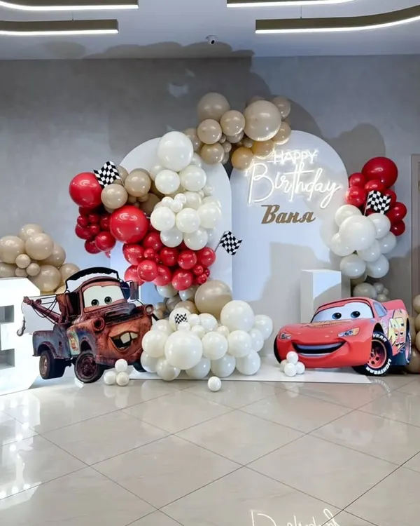 A dynamic Disney Cars themed birthday party for a 3-year-old. The setup includes large cutouts of Lightning McQueen and Mater, a marquee number "3", and a clean, modern backdrop.