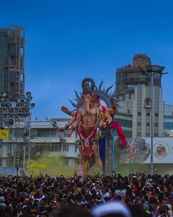 A colossal Ganesha idol towers over a massive crowd during the Ganpati Visarjan festival in Mumbai. The scale of the celebration is immense.
