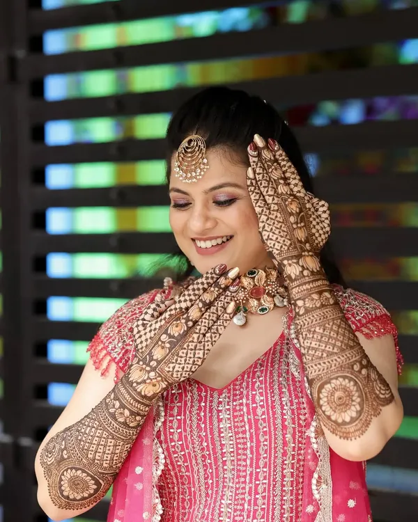 A happy bride admiring her beautiful, detailed mehndi.