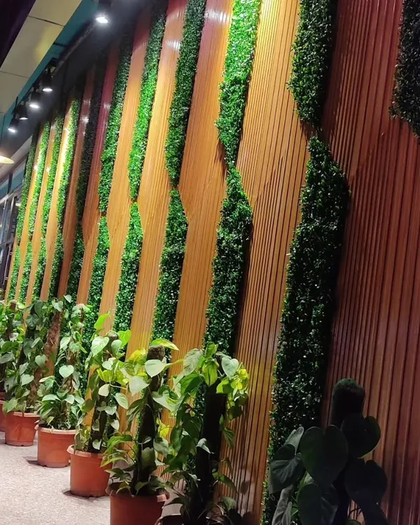 A closer look at the Haldiram's facade installation. The combination of vertical greenery and wood-style panels is fully lit for a dramatic effect at night.