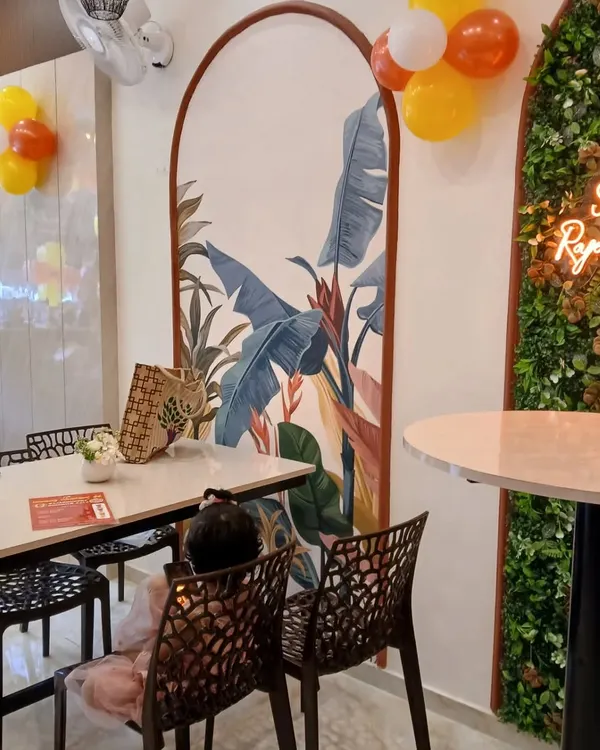 A closer look at the seating area in the cafe project. The custom arched mural with tropical leaf patterns creates a beautiful backdrop. We paired it with durable tables and comfortable, modern chairs to complete the look.