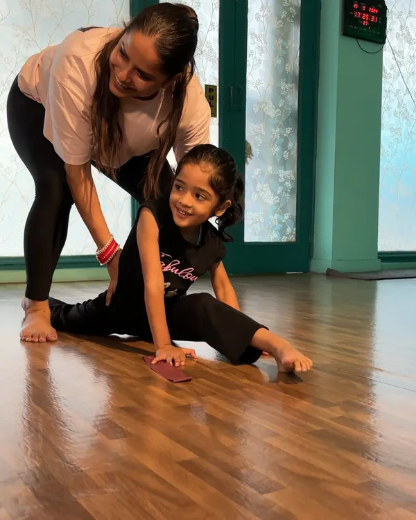 A smiling student works on her splits with my guidance. I ensure every stretch is done correctly to build flexibility safely and celebrate each small achievement.