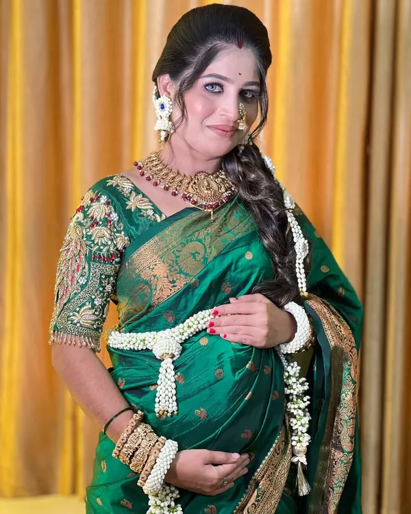A beautiful mom-to-be wearing a classic all-white floral set for her baby shower. The design includes a traditional kamarbandh (waist belt) and hand kalire made from fresh Tagar buds.