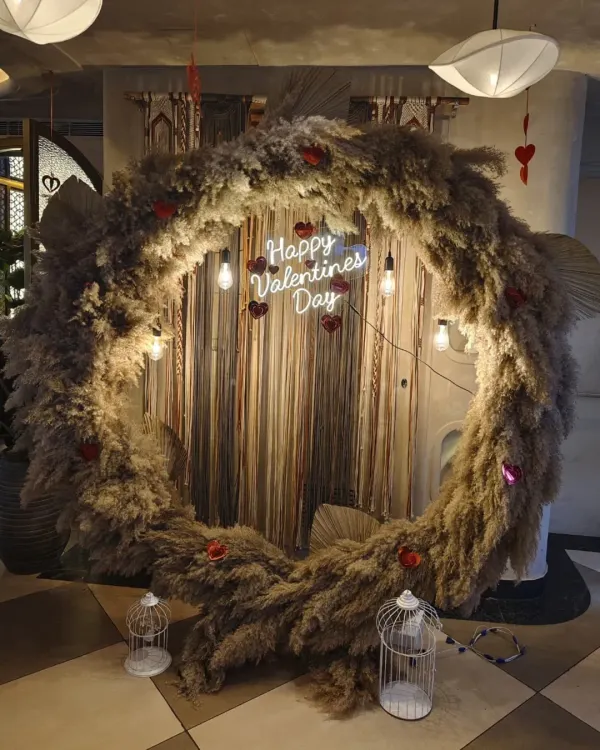 A rustic and romantic Valentine's Day backdrop. I used a large circular frame covered in fluffy pampas grass, with a "Happy Valentines Day" neon sign and hanging lights for a warm, bohemian feel.