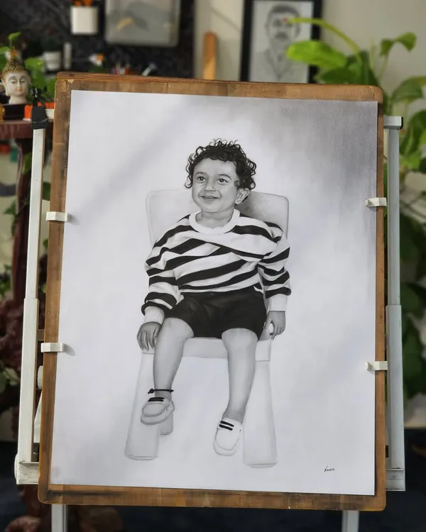 The completed portrait of a young boy on my drawing board, surrounded by the greenery of my studio.