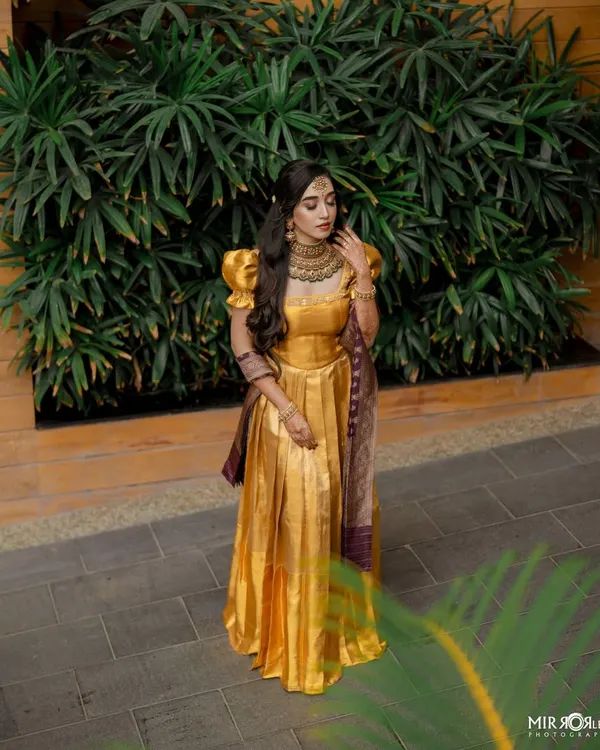 A full-length shot of a client in a beautiful golden gown, perfect for a reception or engagement. The makeup is kept elegant and classic, with soft waves in her hair.