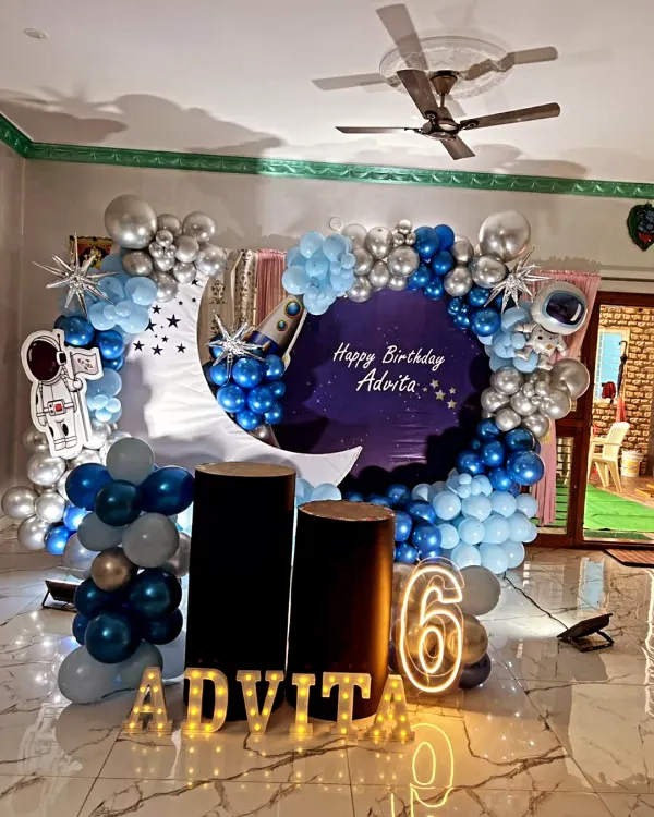 A stunning outer space theme for Advita's 6th birthday, with a crescent moon backdrop and a blue and silver balloon galaxy.