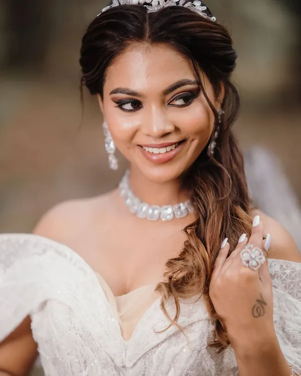 A happy, smiling bride in her beautiful white gown. The makeup is soft and radiant, with a focus on a flawless complexion and a pretty pink lip.
