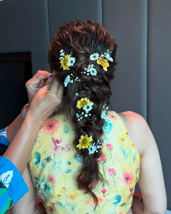 This Haldi bride’s messy fishtail braid is woven with fresh yellow and white flowers, creating a look of effortless, sun-kissed beauty.