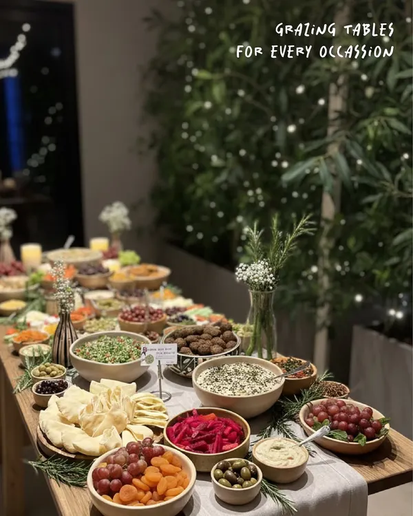 A full view of one of my custom grazing tables set up for a house party. I style each table with an assortment of dips, crackers, breads, olives, fruits, and fresh herbs to create a stunning and delicious spread for your guests.