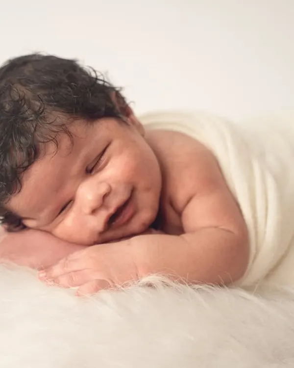 A perfect sleepy smile. I focus on capturing these fleeting moments against a simple, soft white background to keep all the attention on your baby's sweet expression.
