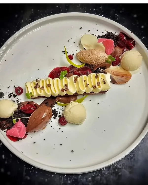 An example of our deconstructed dessert plating. This dish features different elements like chocolate mousse, ice cream, cake crumble, and fruit coulis, arranged artistically on a plate for a gourmet experience.