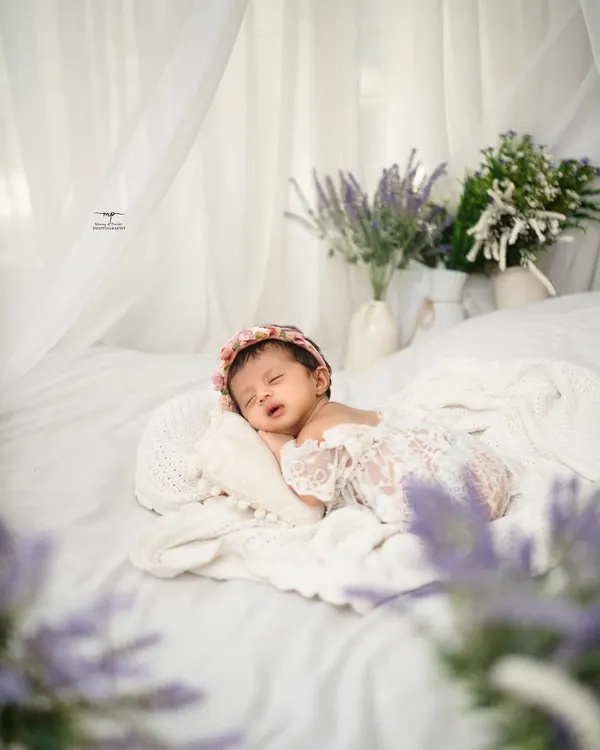 A tiny angel sleeping on a bed of white. This simple, light-filled setup creates a truly ethereal and timeless portrait.