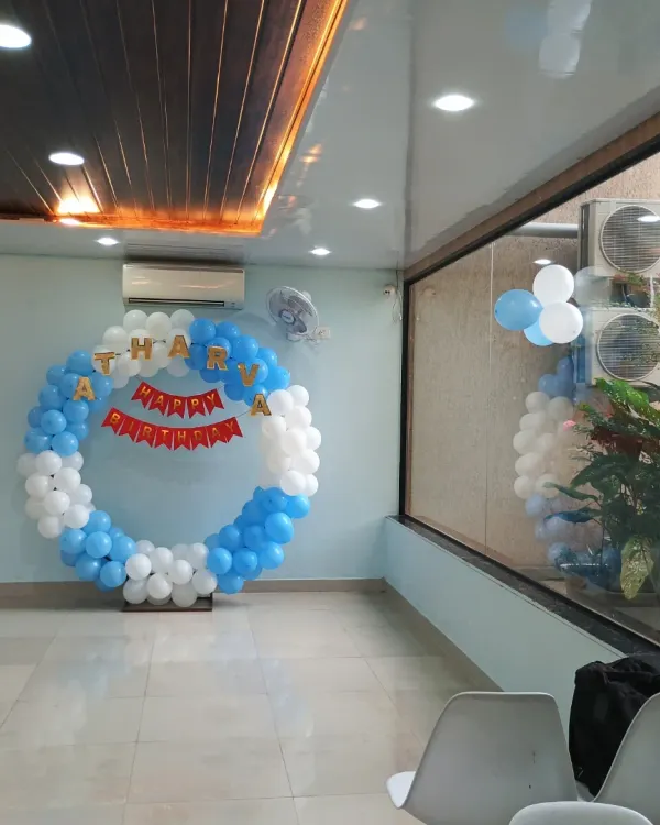A classic blue and white circular balloon ring decoration for a birthday party. This simple yet elegant setup is perfect for photo opportunities and as a cake-cutting backdrop.