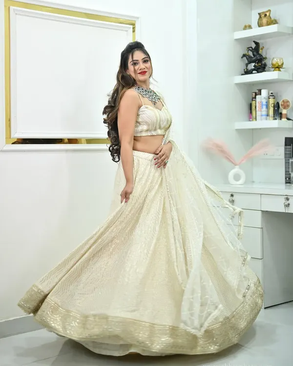 A beautiful ivory lehenga with delicate chikankari work and a gold border. The model's twirl shows off the graceful movement and full flare of the skirt.