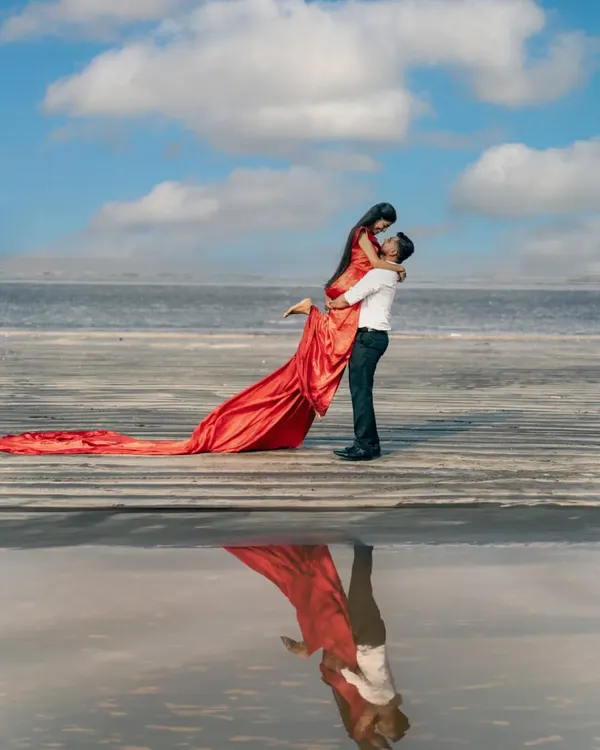 A breathtaking pre-wedding moment captured on the beach, with the couple's reflection creating a perfect mirror image. This shot combines romance, nature, and a touch of cinematic magic, ideal for couples looking for a dramatic beach pre-wedding photoshoot.