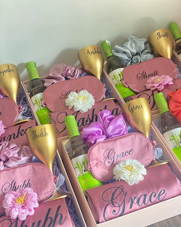 A toast to your bridal party! This bridesmaid hamper includes a personalized unbreakable wine glass, a mini bottle of white wine, a custom satin eye mask and robe, and a matching scrunchie. It's the perfect way to pop the question to your girls.