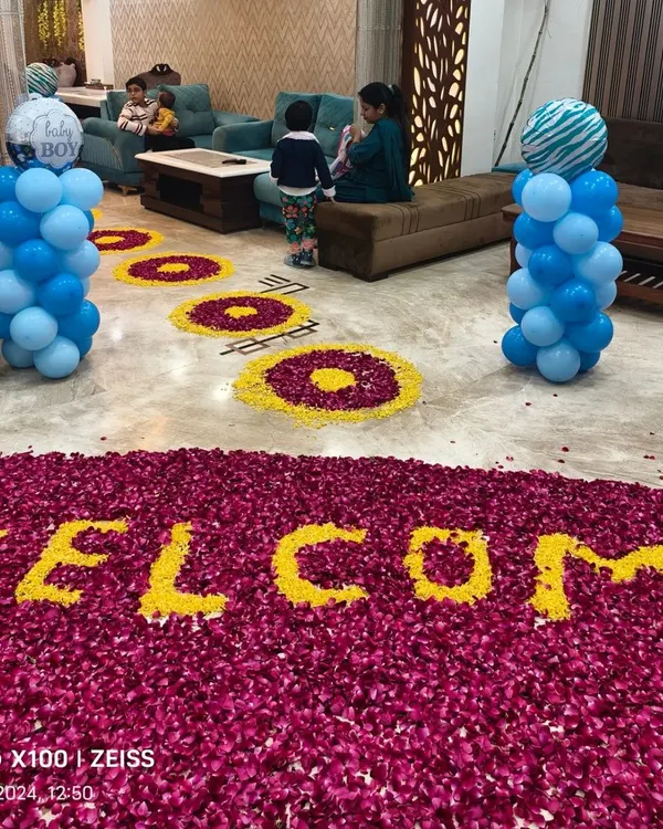 A heartwarming 'Welcome Baby' decoration for a baby boy's arrival. The floor is decorated with a large message made from flower petals and flanked by blue balloon pillars.