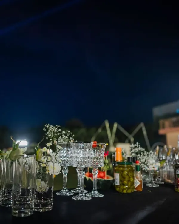 An elegant bar setup at night, with carefully arranged glassware, premium spirits, and fresh floral decorations. We believe the bar should be as beautiful as the rest of your event decor.