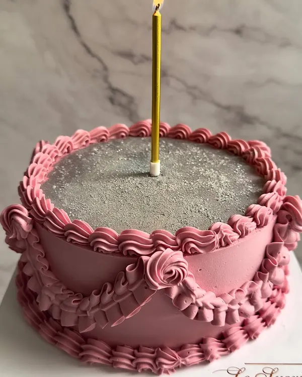 A vintage dream in pink and silver. This cake features classic Lambeth-style piping with delicate ruffles and a sparkling silver top, perfect for a truly special celebration.