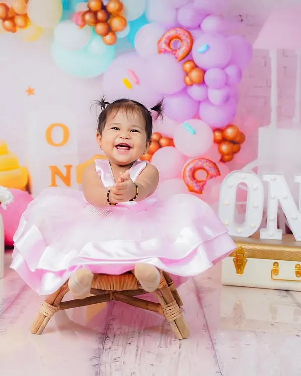 A perfect first birthday portrait with a sweet candy-themed setup. Her joyful laugh is the highlight of this entire session.