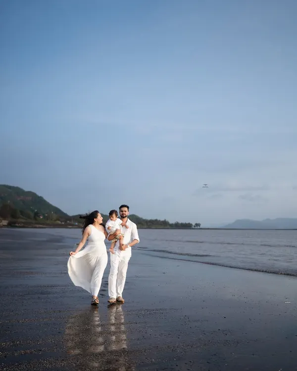 A beautiful family walk along the shoreline. The expecting mother's white dress flows in the breeze, creating a sense of freedom and joy in this outdoor maternity photo.