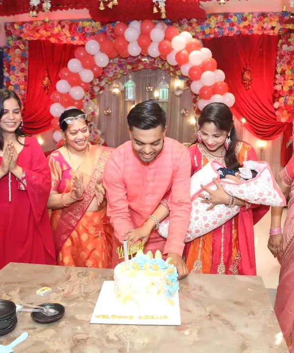 The cake-cutting ceremony at a newborn's welcome party, with the whole family gathered around, clapping and celebrating the new arrival. A classic, happy moment.