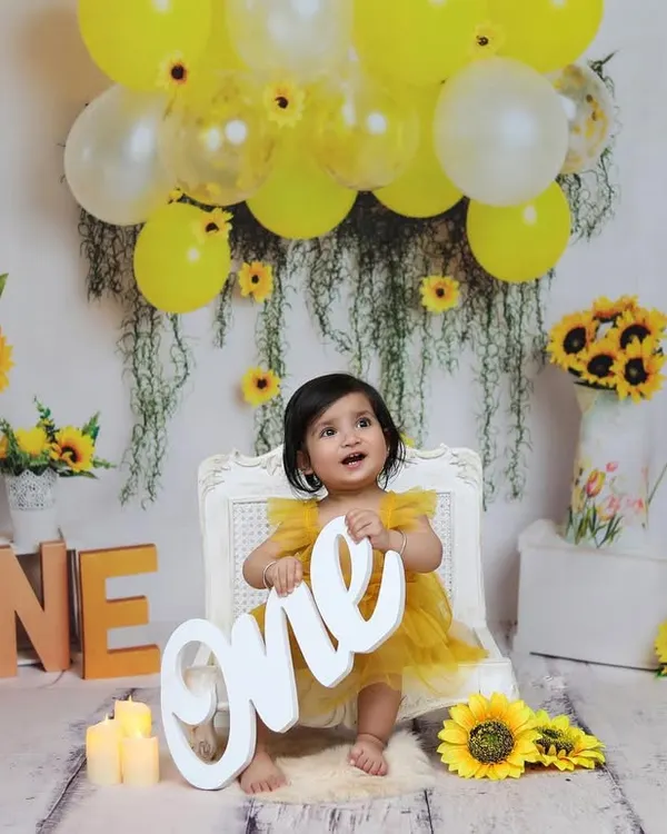 A wide shot of the complete sunflower-themed setup, showing how all the elements like props, balloons, and lighting come together for a first birthday portrait.