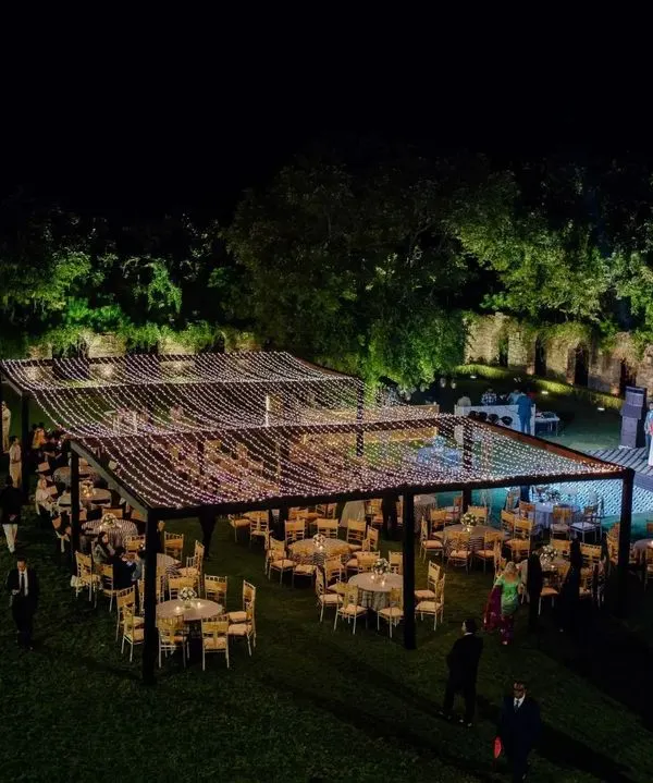 A wide-angle view of the spectacular outdoor reception at Alila Fort. The large dining area under a ceiling of fairy lights, with a beautifully lit stage, showcases the grand scale of the event.