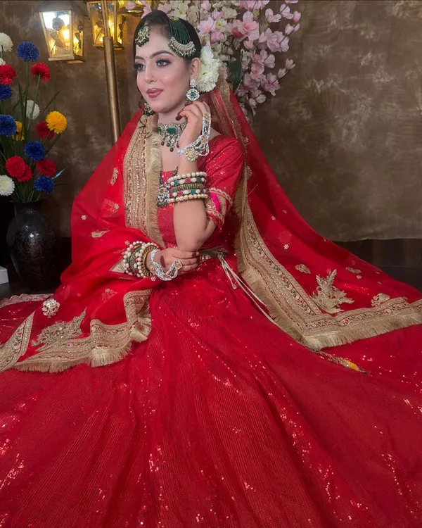 A stunning Muslim bride look in a classic red sequin lehenga. The highlight is the green beaded jewellery set, including a passa, choker, and layered necklace, creating a beautiful color contrast.