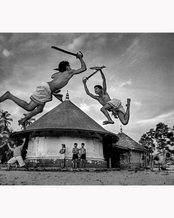 This is a moment of peak action from a Kalaripayattu practice in Kerala. I captured these two warriors mid-air to freeze the raw power and grace of this ancient martial art. This black and white fine art print emphasizes the dramatic form and timeless nature of their discipline.
